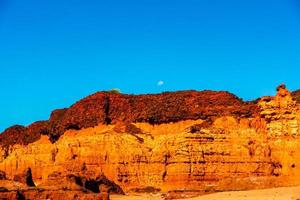 Moon rising over red cliffs photo