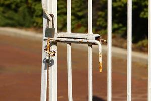 An iron padlock hangs on a closed gate photo