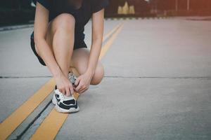 joven corredora de fitness que se ata los cordones de los zapatos antes de correr en el parque. foto