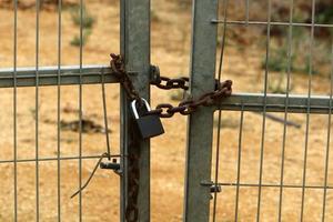 An iron padlock hangs on a closed gate photo