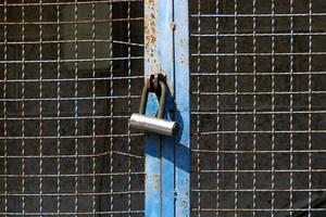 An iron padlock hangs on a closed gate photo