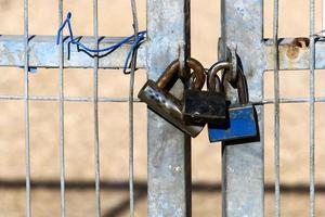 An iron padlock hangs on a closed gate photo