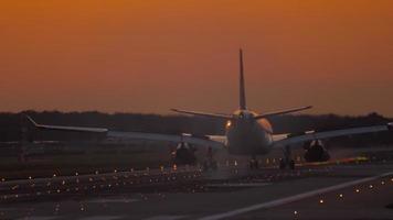 The wide bodied aircraft lands on the illuminated runway in the early morning video