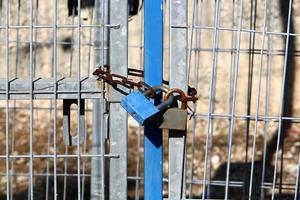 An iron padlock hangs on a closed gate photo