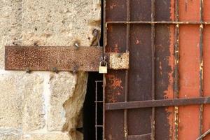 An iron padlock hangs on a closed gate photo