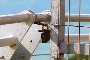 An iron padlock hangs on a closed gate photo