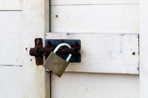 An iron padlock hangs on a closed gate photo