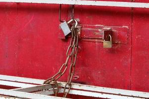 An iron padlock hangs on a closed gate photo