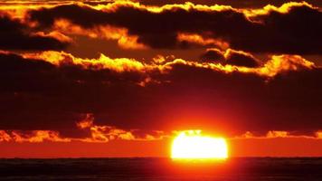 vista panoramica ravvicinata del sole che tramonta oltre l'orizzonte sul mare. video