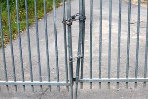 An iron padlock hangs on a closed gate photo