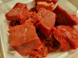 large chunks of raw red beef meat in foam container photo