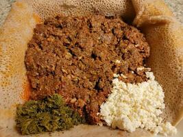 raw beef Ethiopian food called kitfo with bread and greens and cheese photo