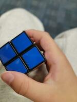 mano de niño sosteniendo un cubo de juguete con cuadrados azules foto