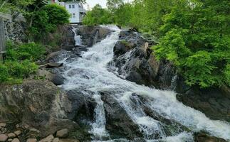 rocks and waterfall or cascade with trees and buildings photo
