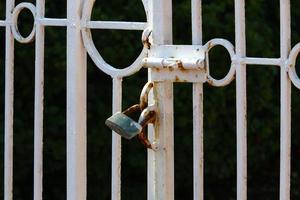 An iron padlock hangs on a closed gate photo