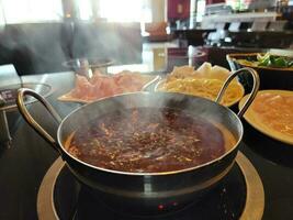 olla caliente china con caldo picante en un tazón en la mesa foto