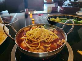 Chinese hot pot with spicy broth in bowl with meat and noodles photo