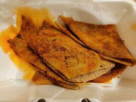 fried Ethiopian bread called injera with spices in container photo