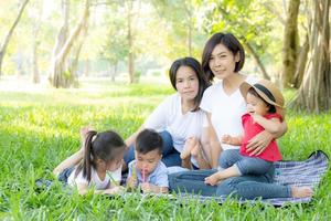 Beautiful young asian parent family portrait picnic in the park, kid or children and mother love happy and cheerful together in summer at garden, lifestyle concept. photo