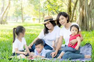 Beautiful young asian parent family portrait picnic in the park, kid or children and mother love happy and cheerful together in summer at garden, lifestyle concept. photo