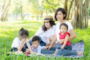 Beautiful young asian parent family portrait picnic in the park, kid or children and mother love happy and cheerful together in summer at garden, lifestyle concept. photo