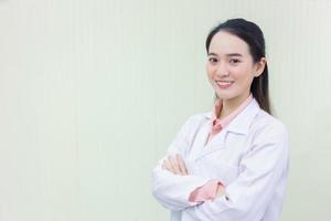 la doctora asiática cruza el brazo y sonríe foto
