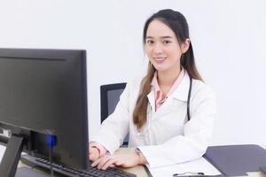 Asian woman doctor is typing on keyboard to record information. photo