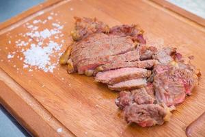 Medium grilled tender deliciously sliced beef laying on salted wooden chopping board on the side is a street food in Thailand. photo