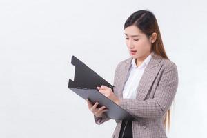 mujer de negocios asiática de pelo largo sostiene el portapapeles en la mano mientras trabaja en casa. foto