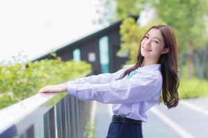 Young Asian student girl in school uniform is smiling with braces on teeth in a park in the middle of the city. photo