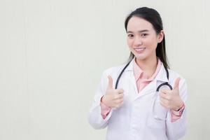 Asian woman doctor shows hand as thump up who wears medical clothing photo