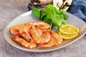 Delicious cooked shrimps in plate isolated on grey background. Boiled prawns photo