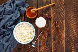 Cottage cheese with honey and berries on wooden background. Light vegetarian breakfast. Top view photo