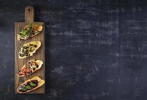 Bruschetta with chicken liver paste. Delicious bruschettas with various fillings. Different bruschetta ob wooden background photo