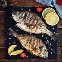 Grilled dorado fish on wooden background. Roasted seafish with spice and herbs photo