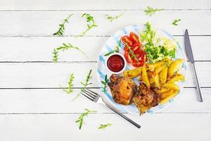 Delicious baked chicken with potatoes on wooden background. Top view photo