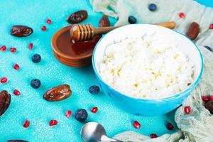 Cottage cheese with honey and berries on blue background. Light vegetarian breakfast photo