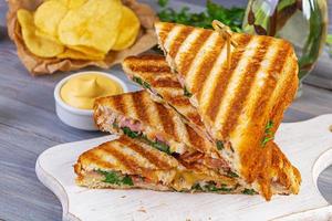 Club sandwich with ham, cheese, tomato, salad and chips photo