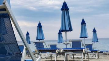 de tumbonas y sombrillas en la arena de la playa, durante un día de verano foto