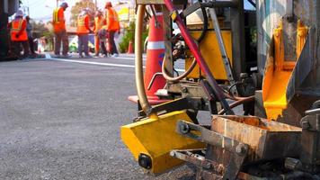 Close up thermoplastic spray marking machine with blurred background of road workers team discussing work on asphalt road in the city photo