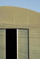 Front view of green sliding door with shadow of cable lines on surface of the old tent warehouse against pale blue sky background in vertical frame photo