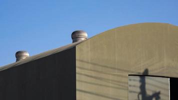 Selective focus at roof ventilators on top of the old tent warehouse against blue sky background photo