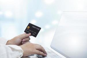 Selective focus at overweight woman's hand holding credit card mock up and using laptop computer in office room photo