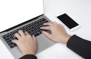 Close up young businessman hand using laptop with smartphone on white table floor photo