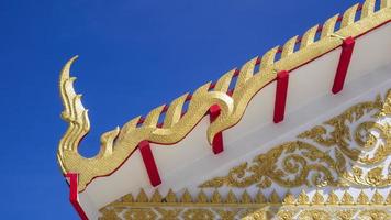 Golden Naga structure pattern on ornamental Thai temple roof against blue sky background photo