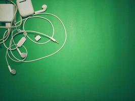 phone charger and white headphones Placed on a green background with vignettes, vintage style, copy space. photo