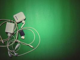 phone charger and white headphones Placed on a green background with vignettes, vintage style, copy space. photo