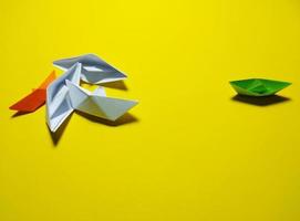 falling green white paper boat The yellow background gives the concept of leadership and ineffective management. causing failure to feel broken, unsuccessful, selfish photo
