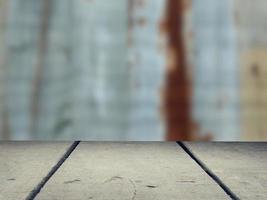 An old wooden plank with a blurry background, a galvanized wall with brown rust marks Used as a counter for display and advertising. photo