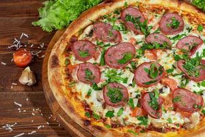 Pizza with bacon and cheese, herbs and cherry tomatoes. With mozzarella, shrimps and octopuses, mussels and other products on a wooden background. photo